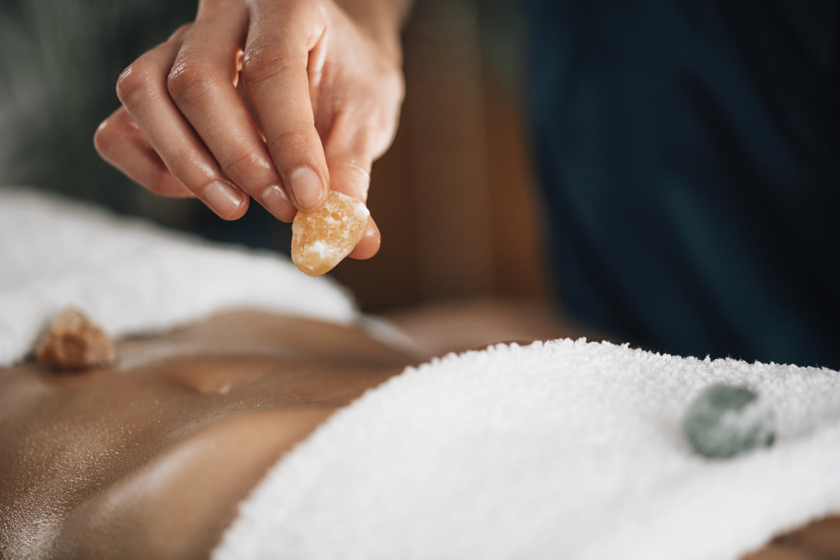 Close-up of a person holding a citrine crystal during a healing session, placing it on a patient's body."