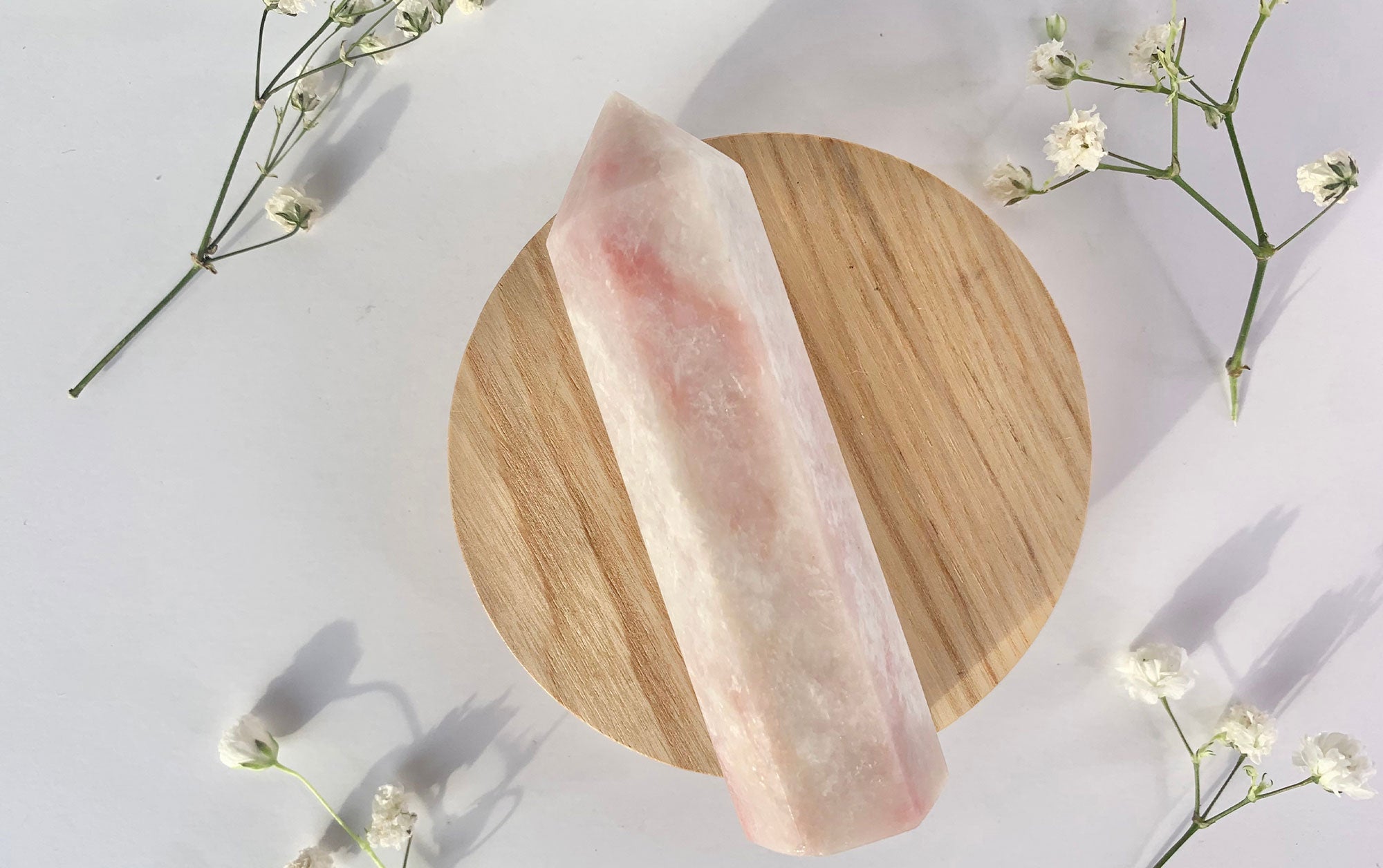 A smooth, light pink Pink Opal gemstone with a polished surface and subtle, soft color variations