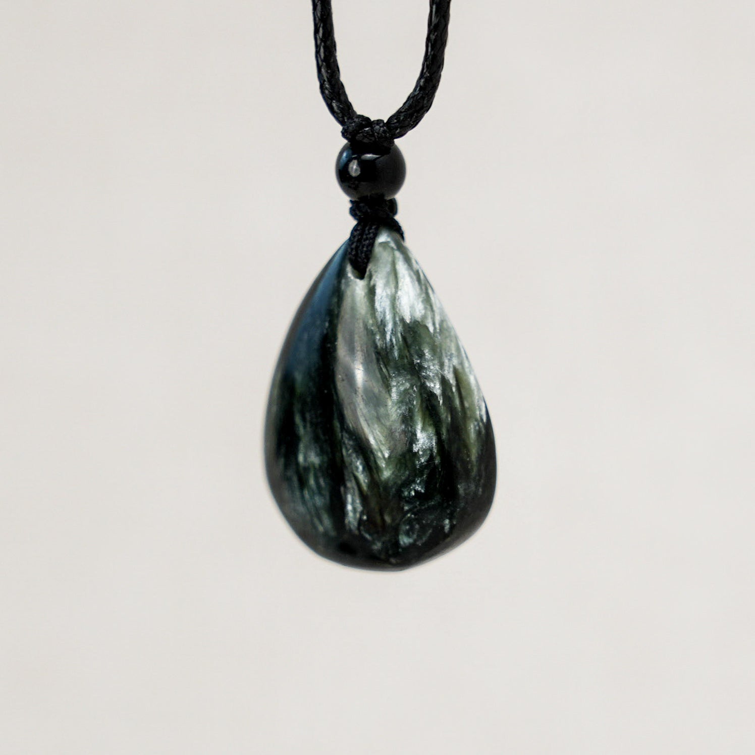 Beautiful seraphinite teardrop pendant that showcases the stone's unique green hues and feather-like patterns.