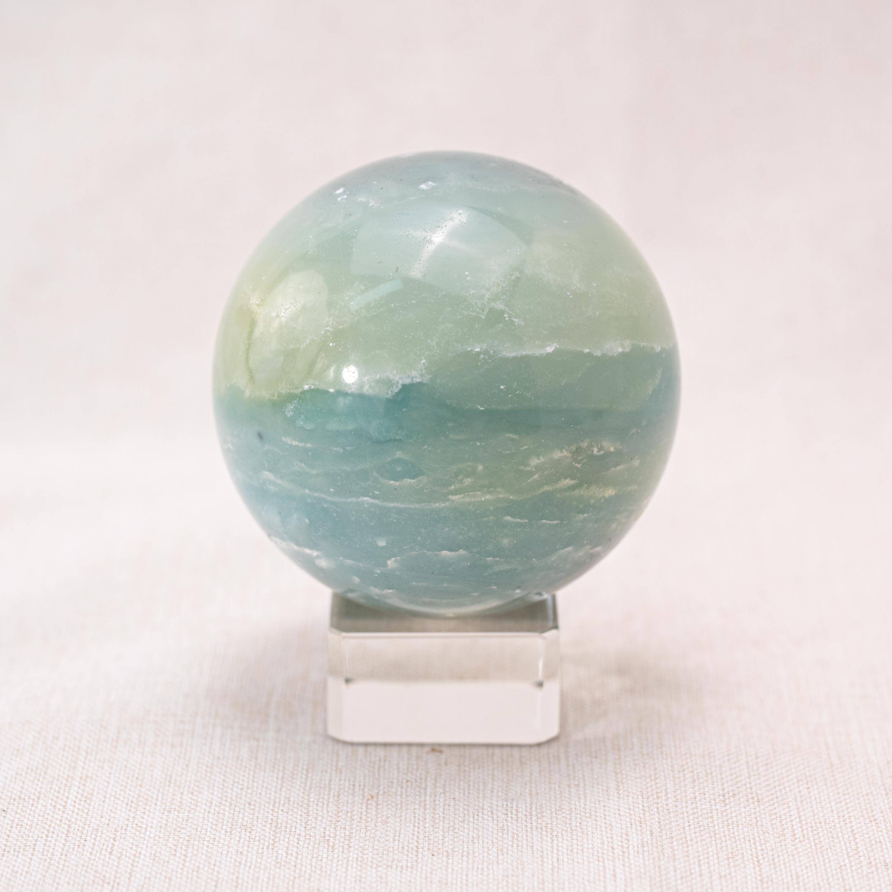 Amazonite sphere with turquoise-green color, used for healing and stress relief.