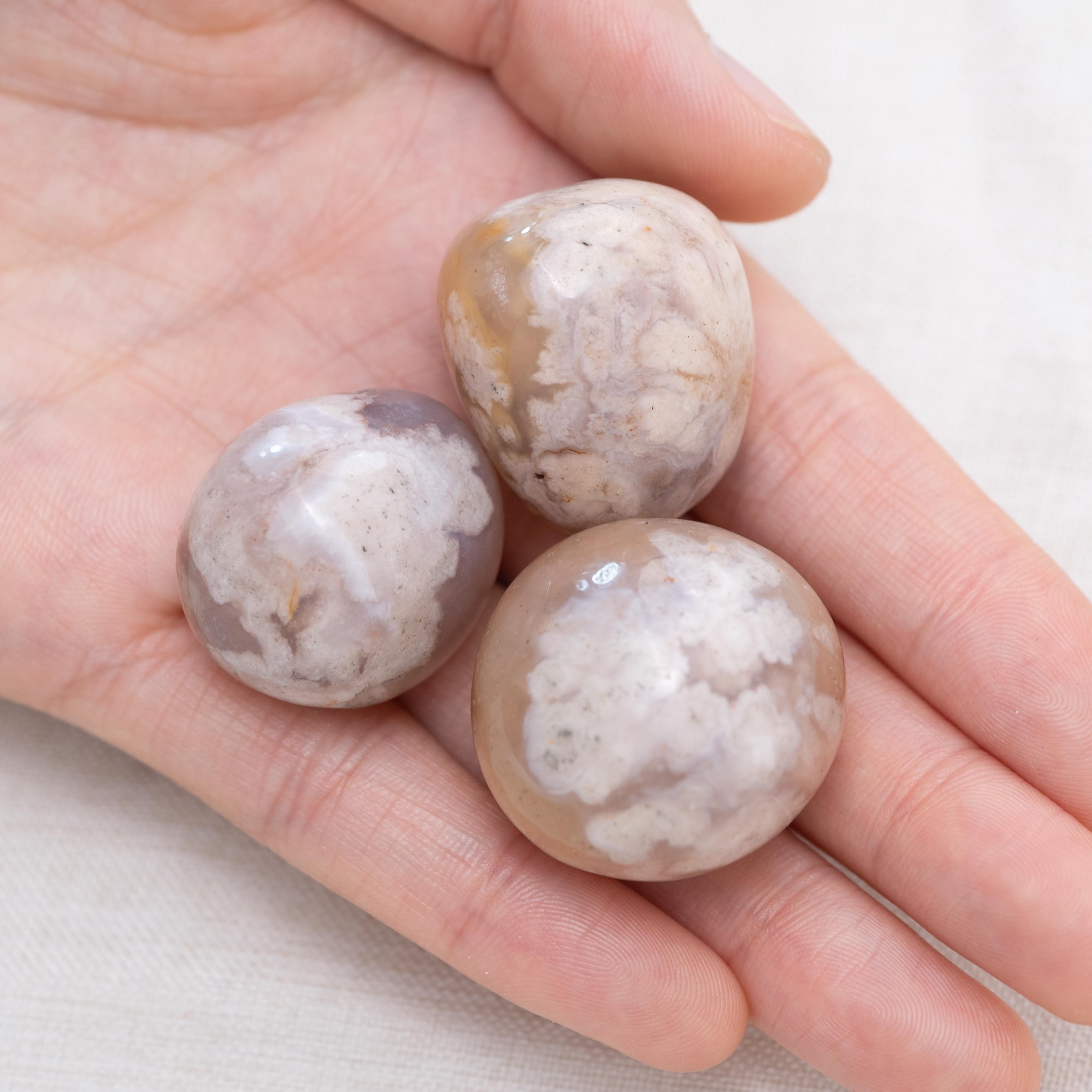 Hand holding Flower Agate tumbled stone for growth and joy
