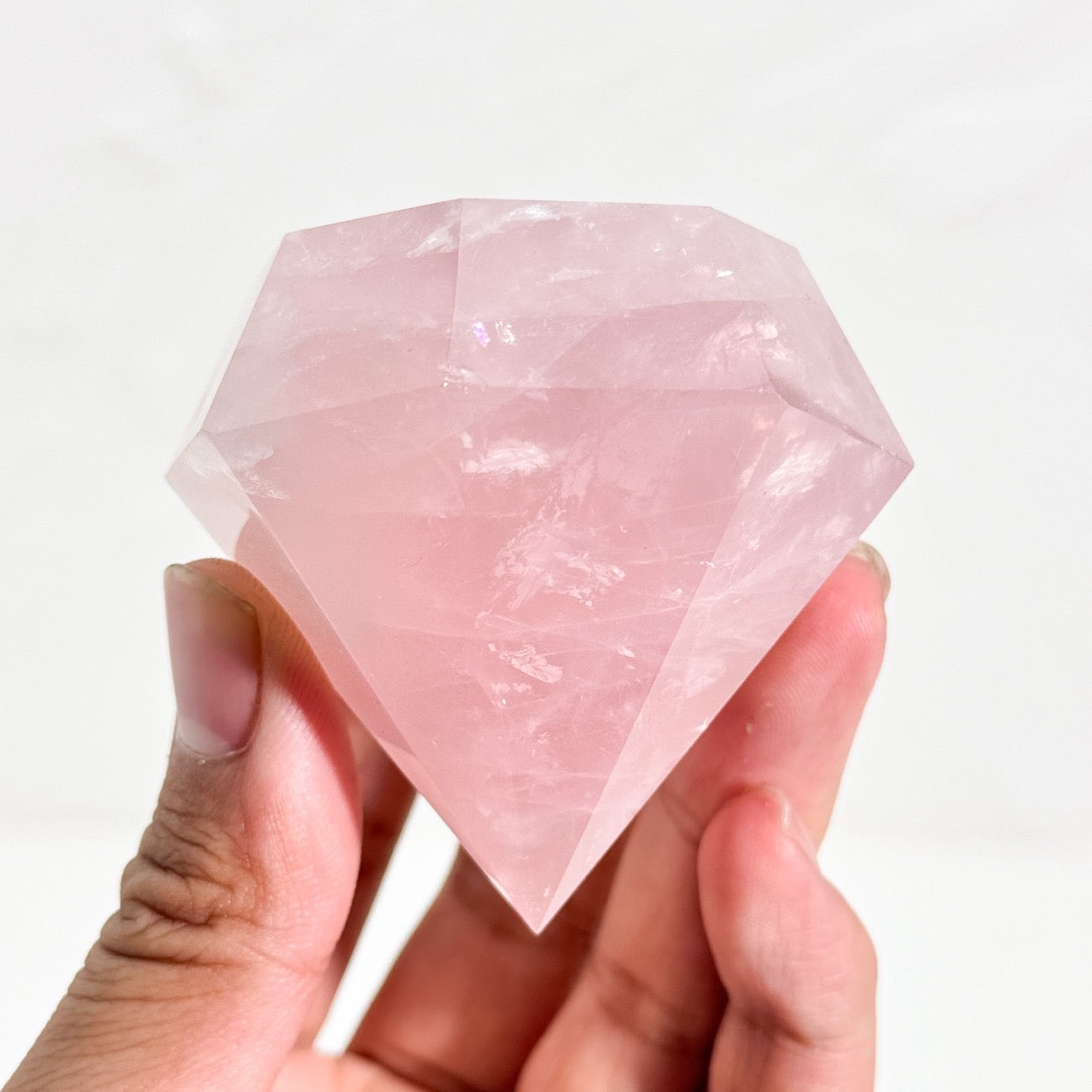 Hand holding rose quartz diamond point crystal