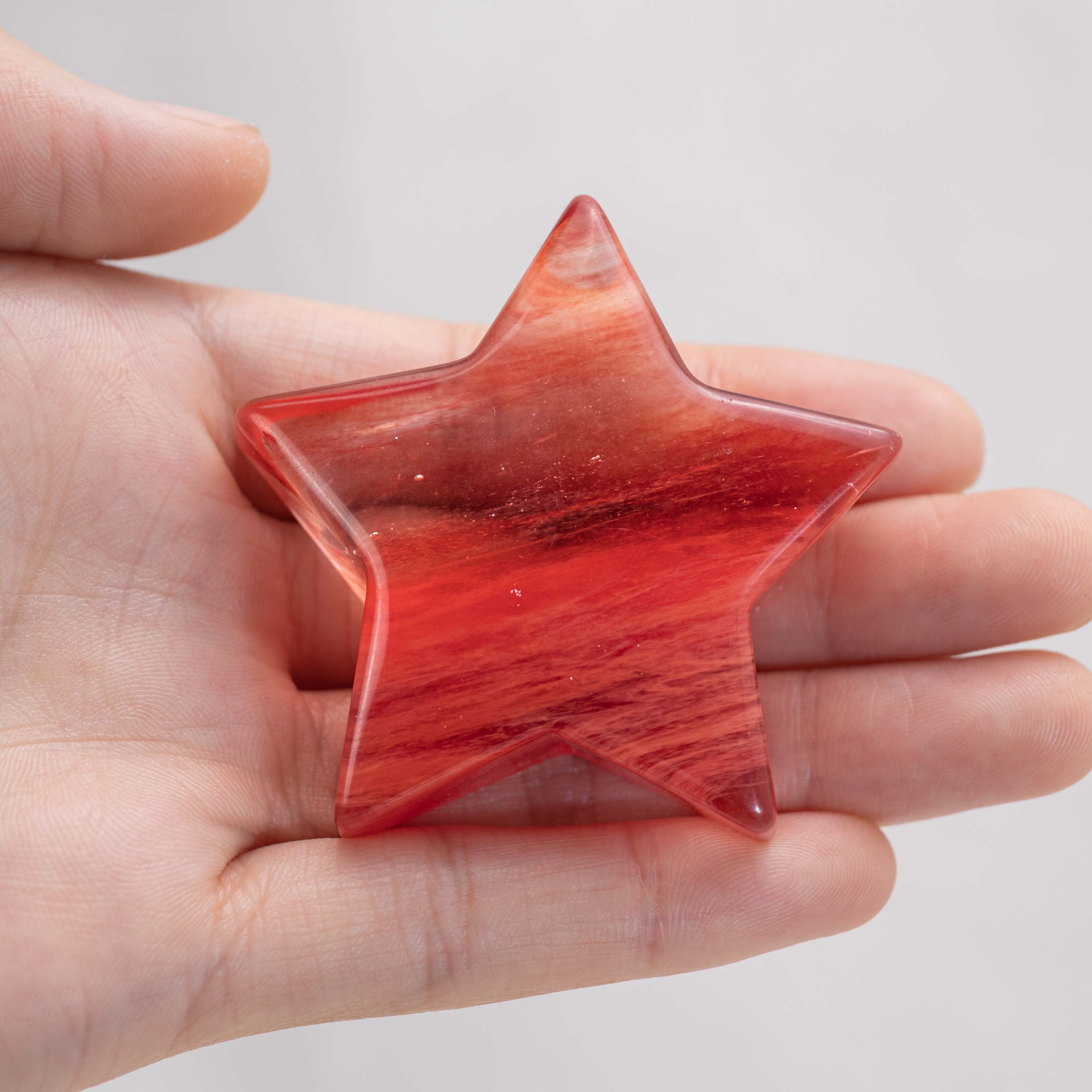 Hand holding Red Smelting Quartz Star/Moon Palm Stone