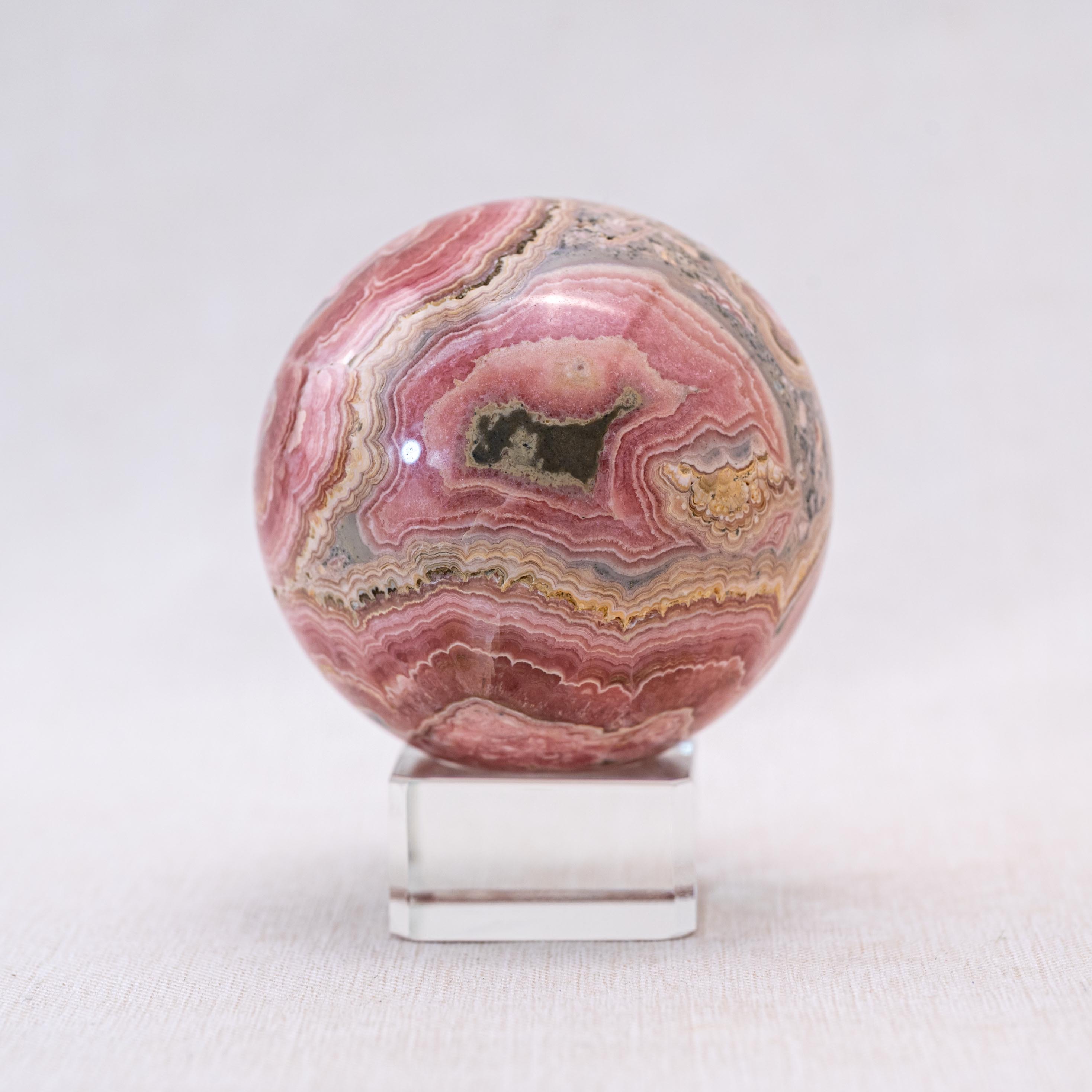 This natural rhodochrosite sphere enhances love and compassion.