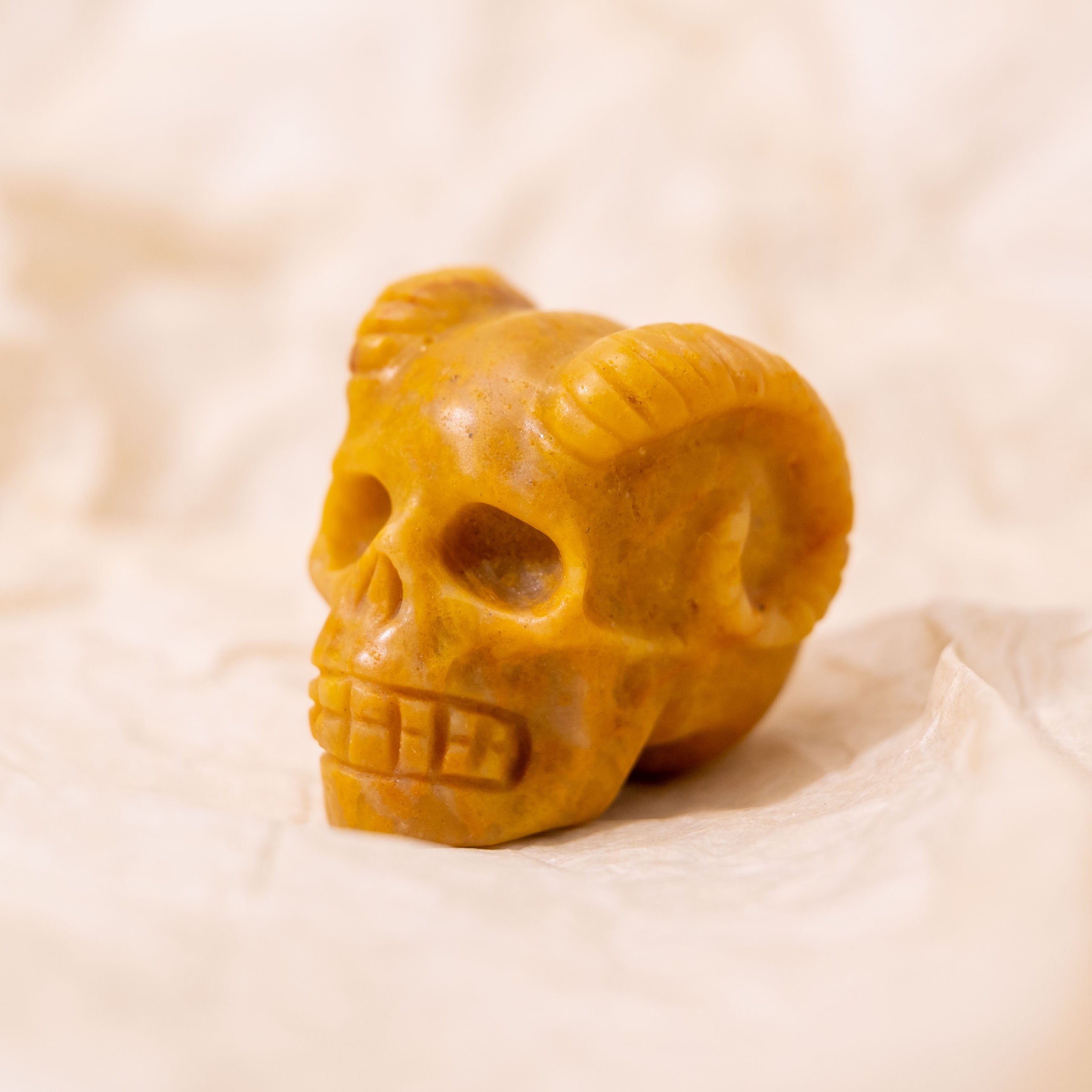 Crafted from Yellow Jade, this Mini Ram Horned Skull promotes joy, energy, and well-being, making it a unique decorative piece.
