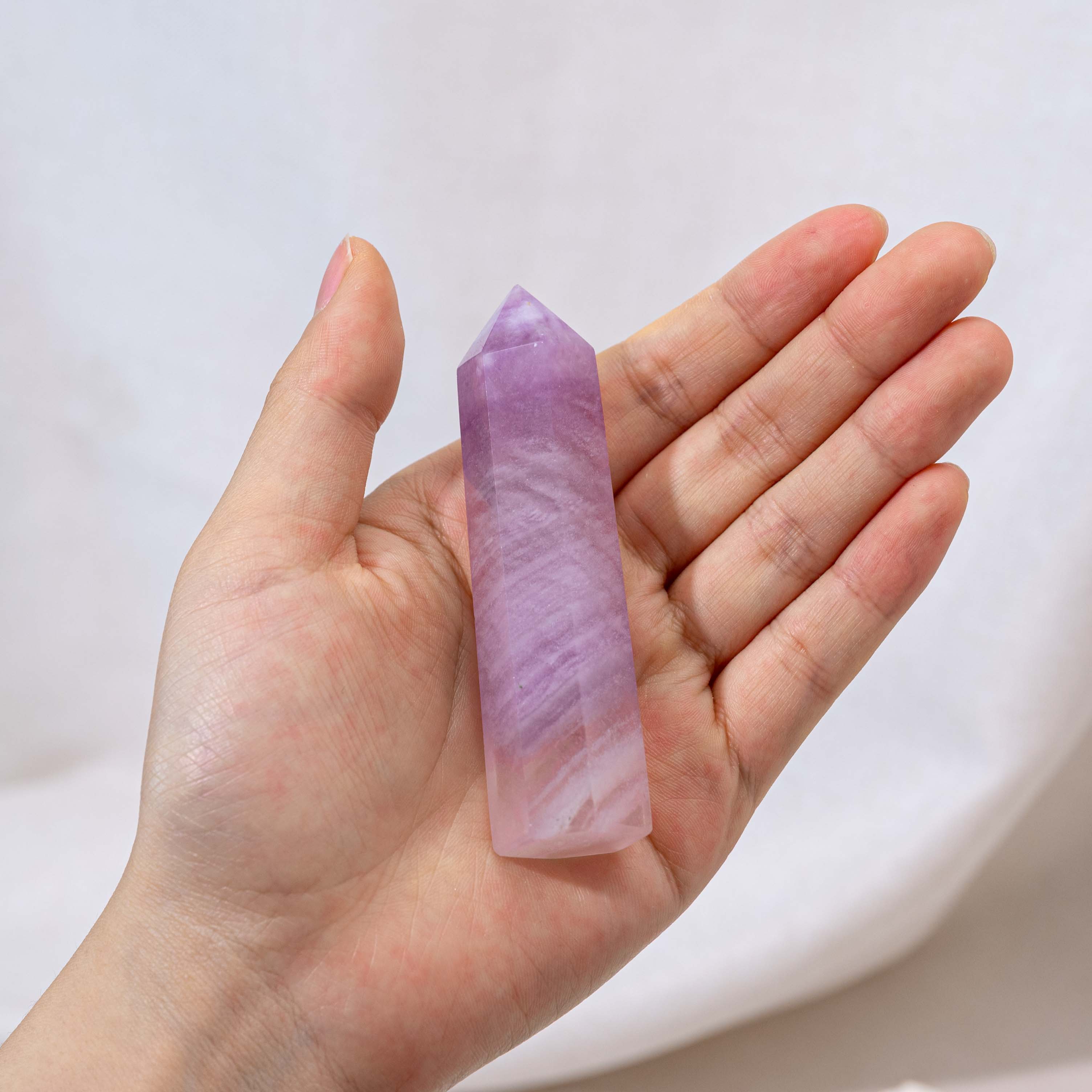 A hand-held Purple Fluorite Point, showcasing its vibrant color