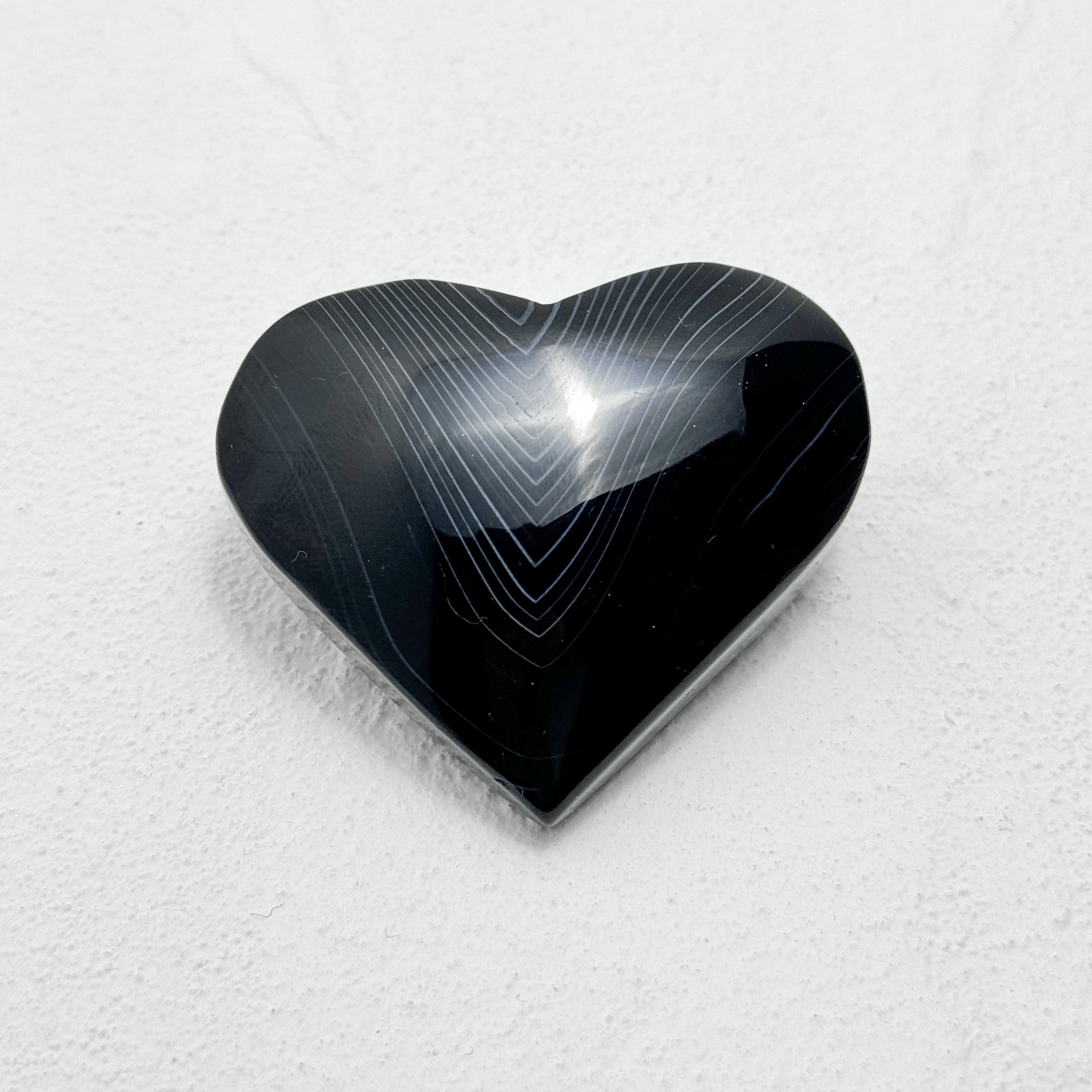 Heart-shaped black polished stone with unique lace-like patterns